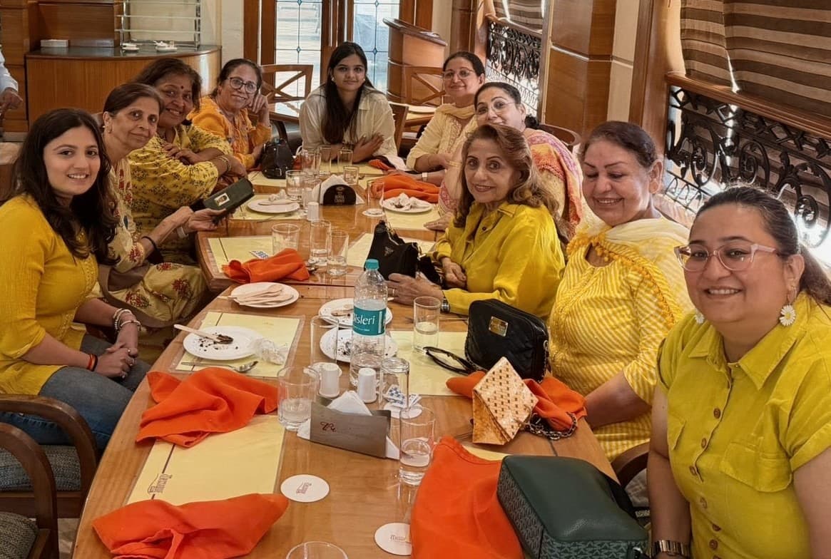 Members of the Andheri West club around a long table at a restaurant, dressed in yellow, on a group lunch outing.