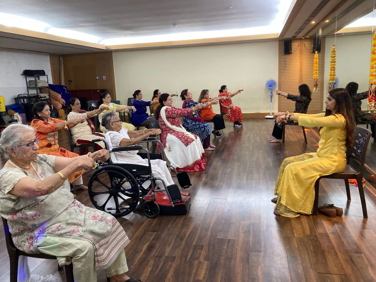 A Zealver instructor leading a seated session, with members in chairs and a wheelchair user taking part